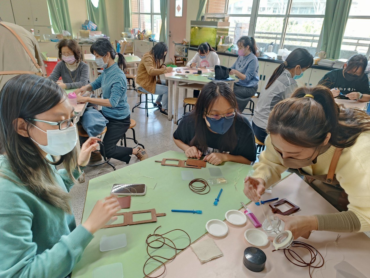 Students stitching leather pieces in the workshop during a class