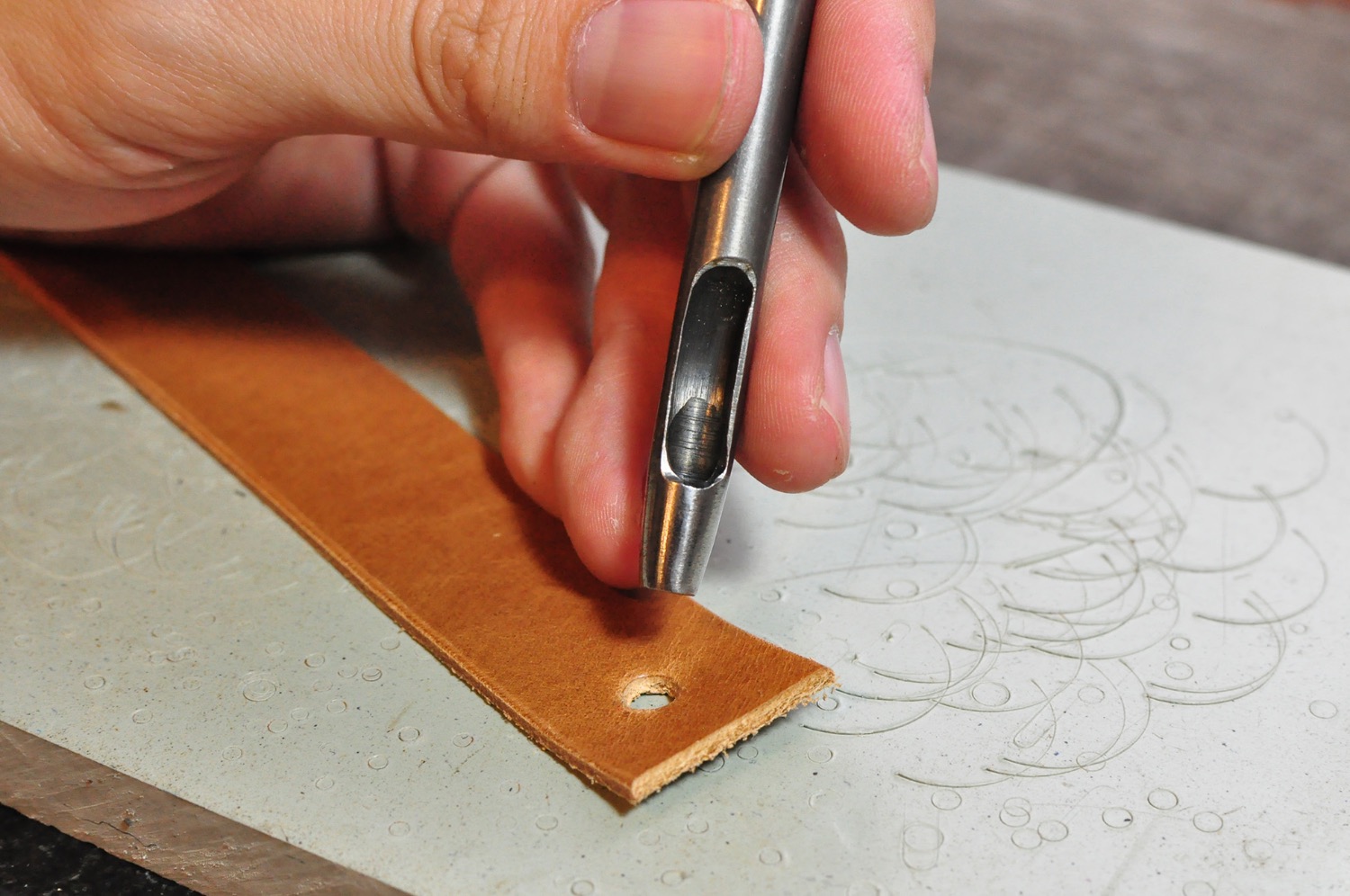 Punching holes in a belt with a round hole punch, a leather handcraft tool demonstration